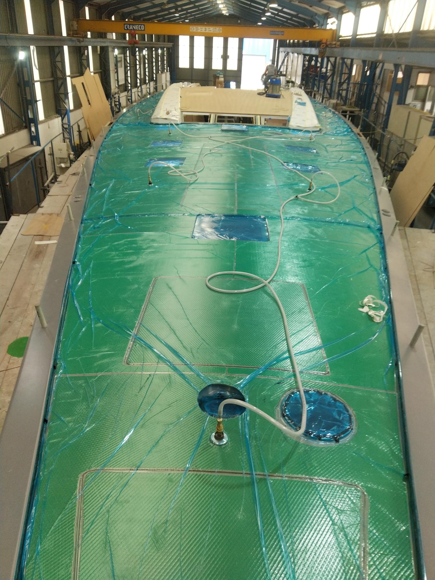 Image montrant le processus de pose sous vide d'un revêtement en PVC imitation teck sur un pont de bateau.